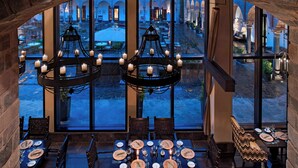 A dining area with a table set for four, large windows, and two chandeliers. - JW Marriott El Convento Cusco (Cusco)