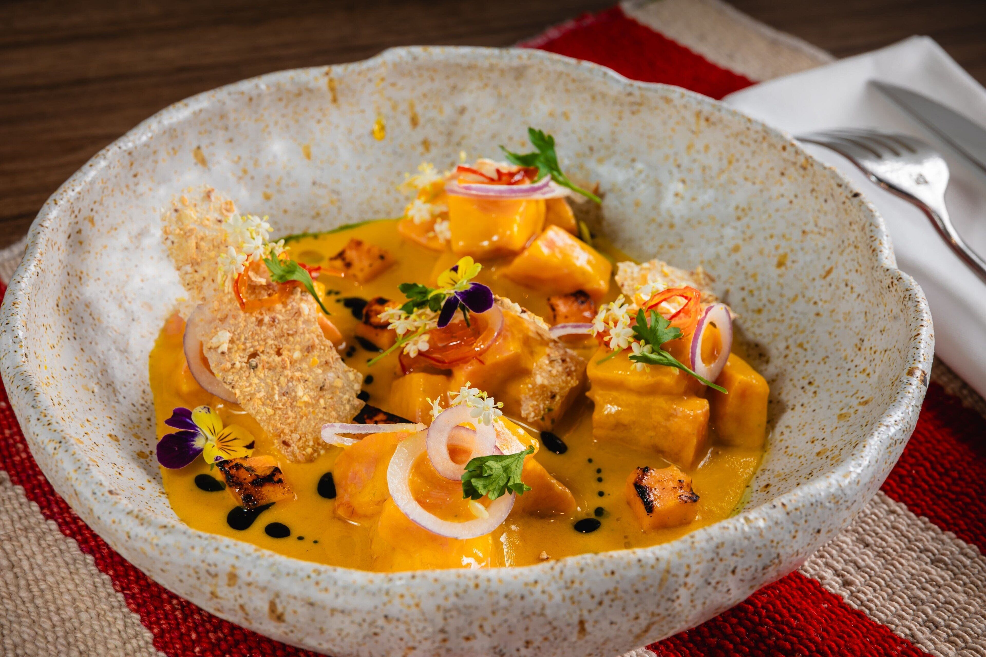 A bowl of food with various garnishes and a spoon.