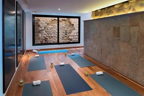 A yoga room with wooden flooring, yoga mats, and towels.