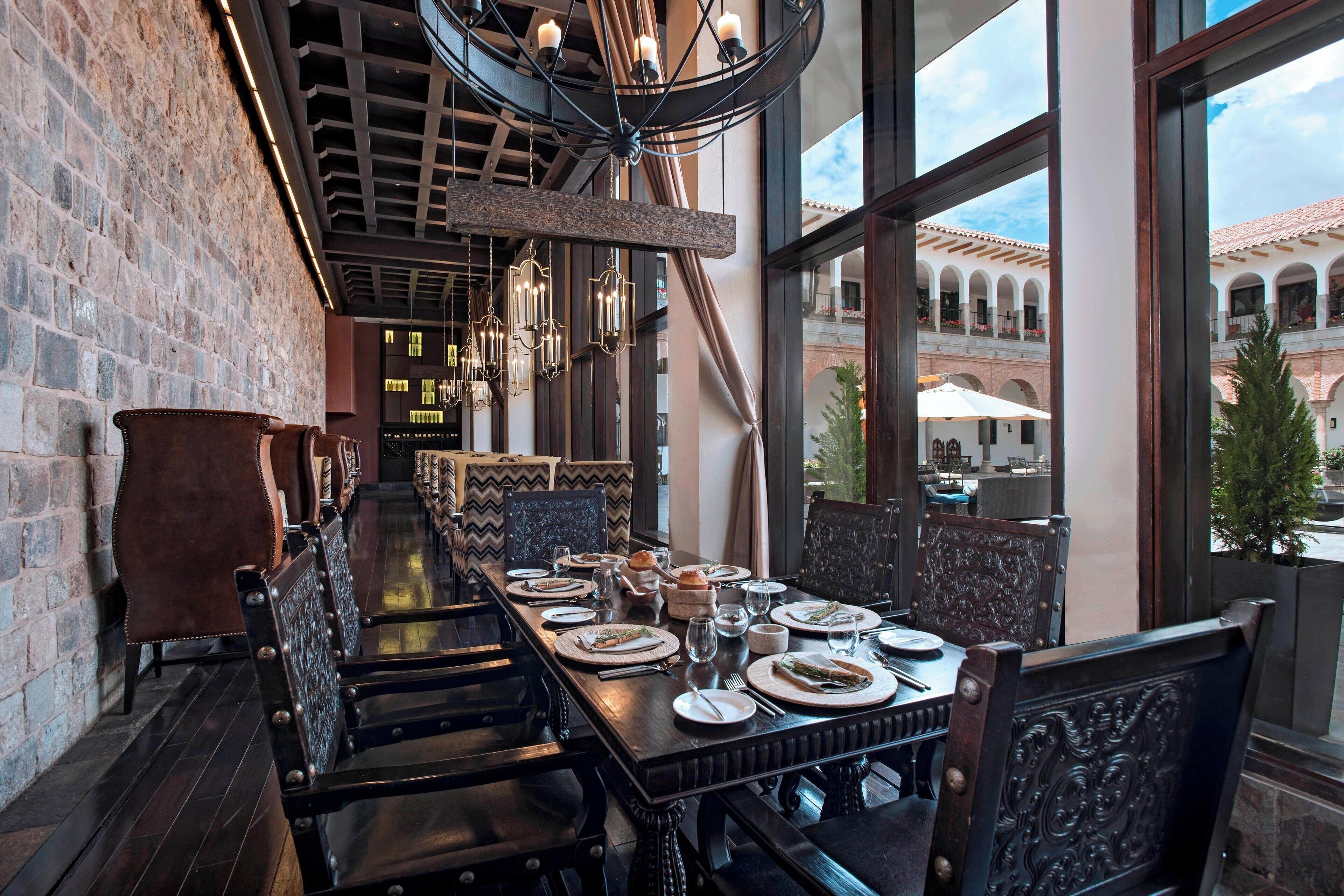 A long dining table set with plates, glasses, and cutlery, flanked by upholstered chairs.