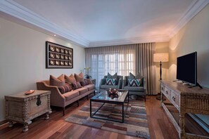 A living room with a sofa, a coffee table, a TV, and a decorative wall piece.