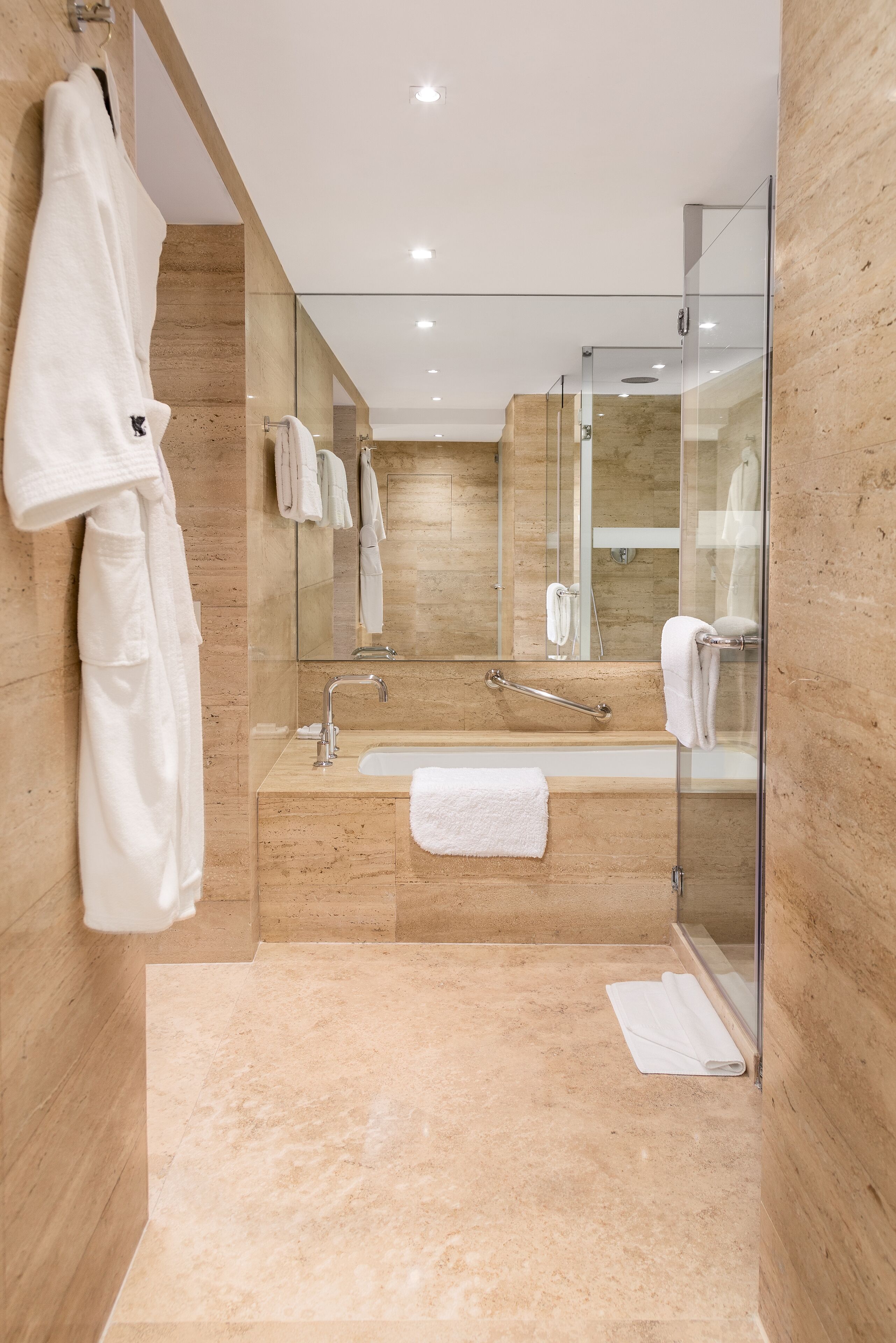 A modern bathroom with a glass shower enclosure, a bathtub, and a sink.