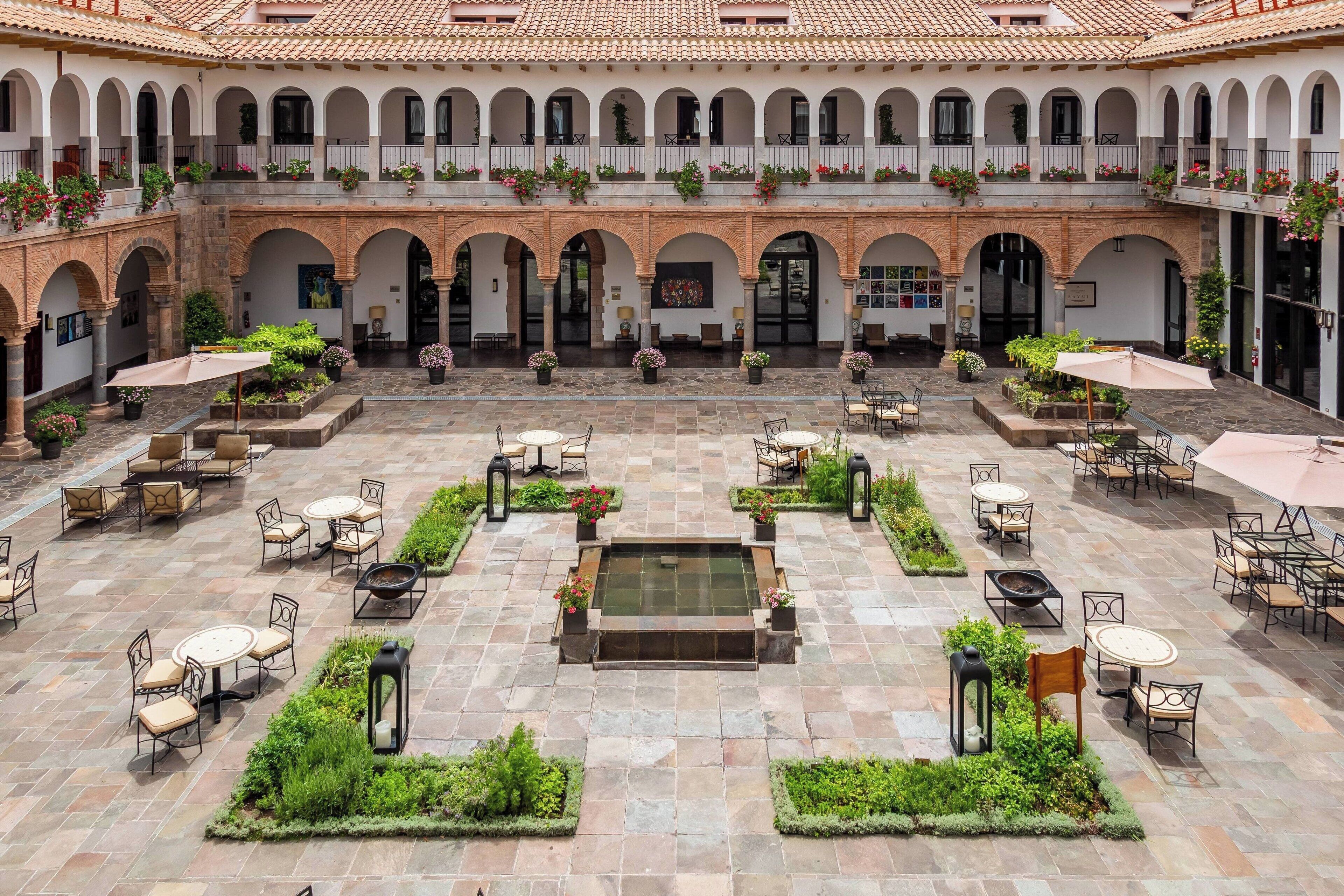 A courtyard with multiple levels of arches, outdoor seating areas, and a central water feature.