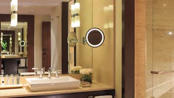 A bathroom with a large mirror, a sink, and a vase of white flowers.