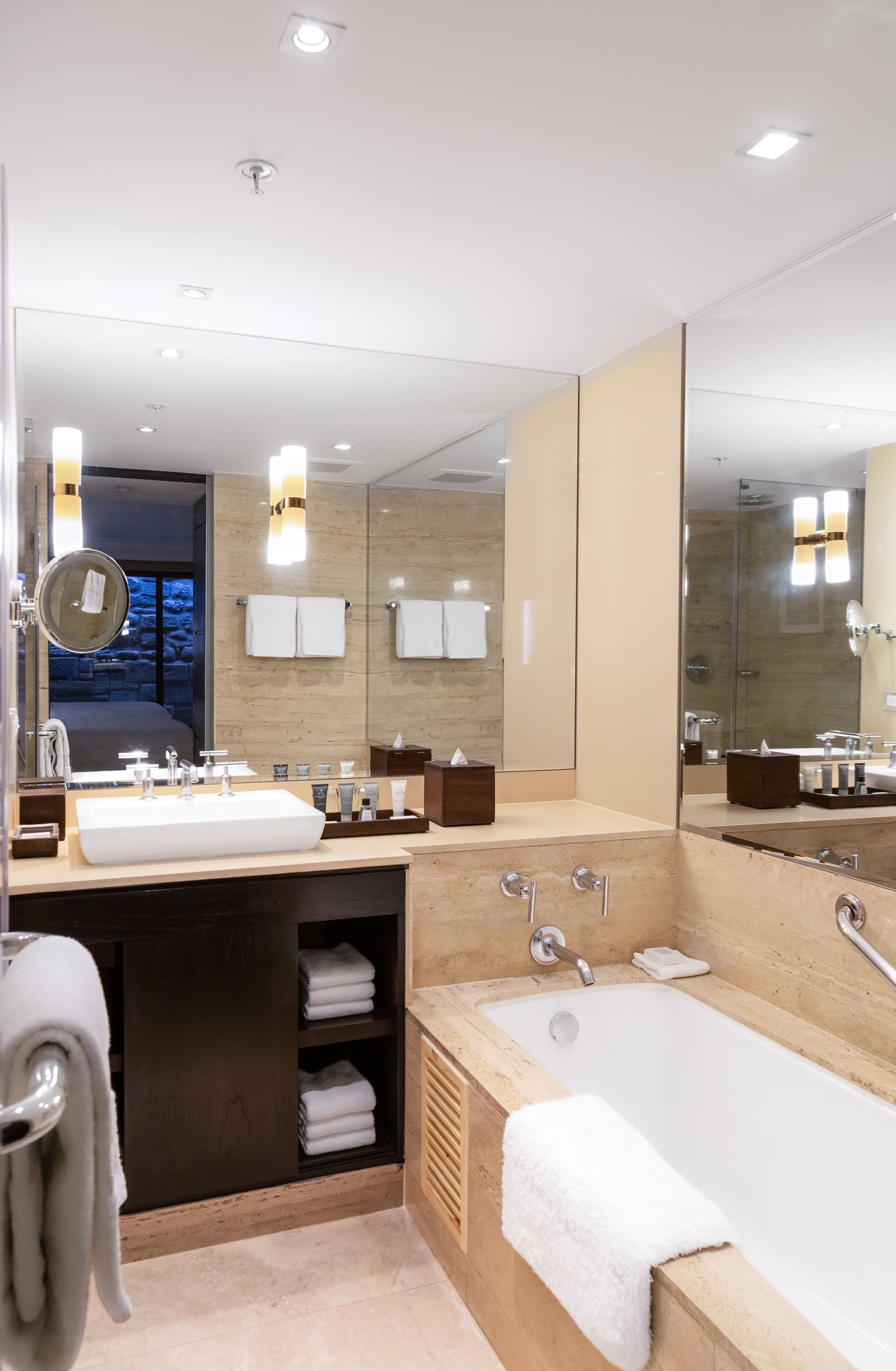 A modern bathroom with a large mirror, two sinks, a bathtub, and a shower.