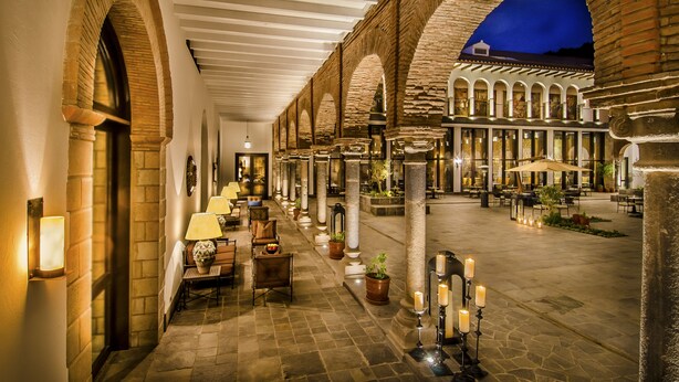 A covered outdoor area with stone arches, tables, chairs, and potted plants. - JW Marriott El Convento Cusco (Cusco)