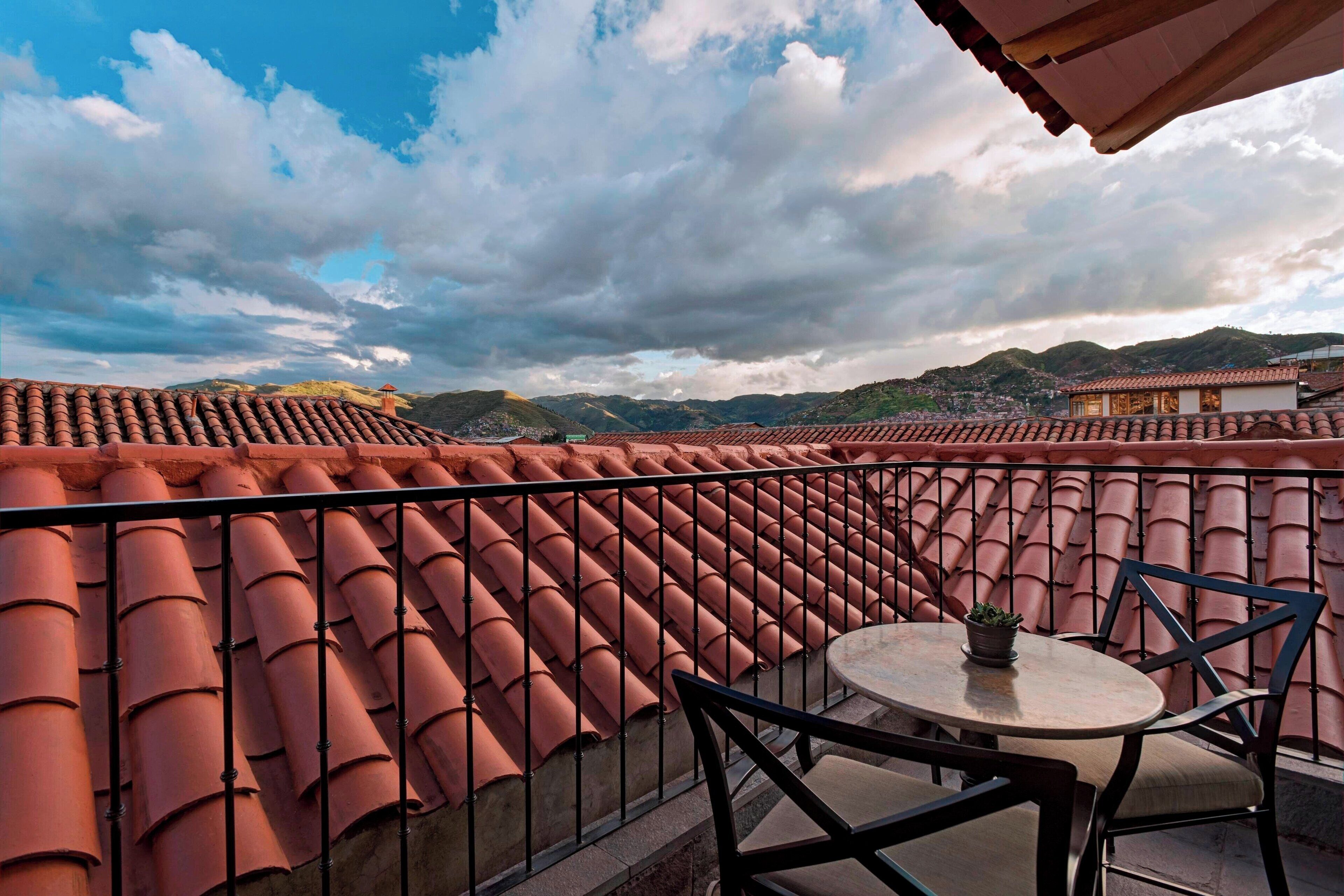 Una terraza con tejas de terracota, una mesa redonda con sillas y una planta en maceta.