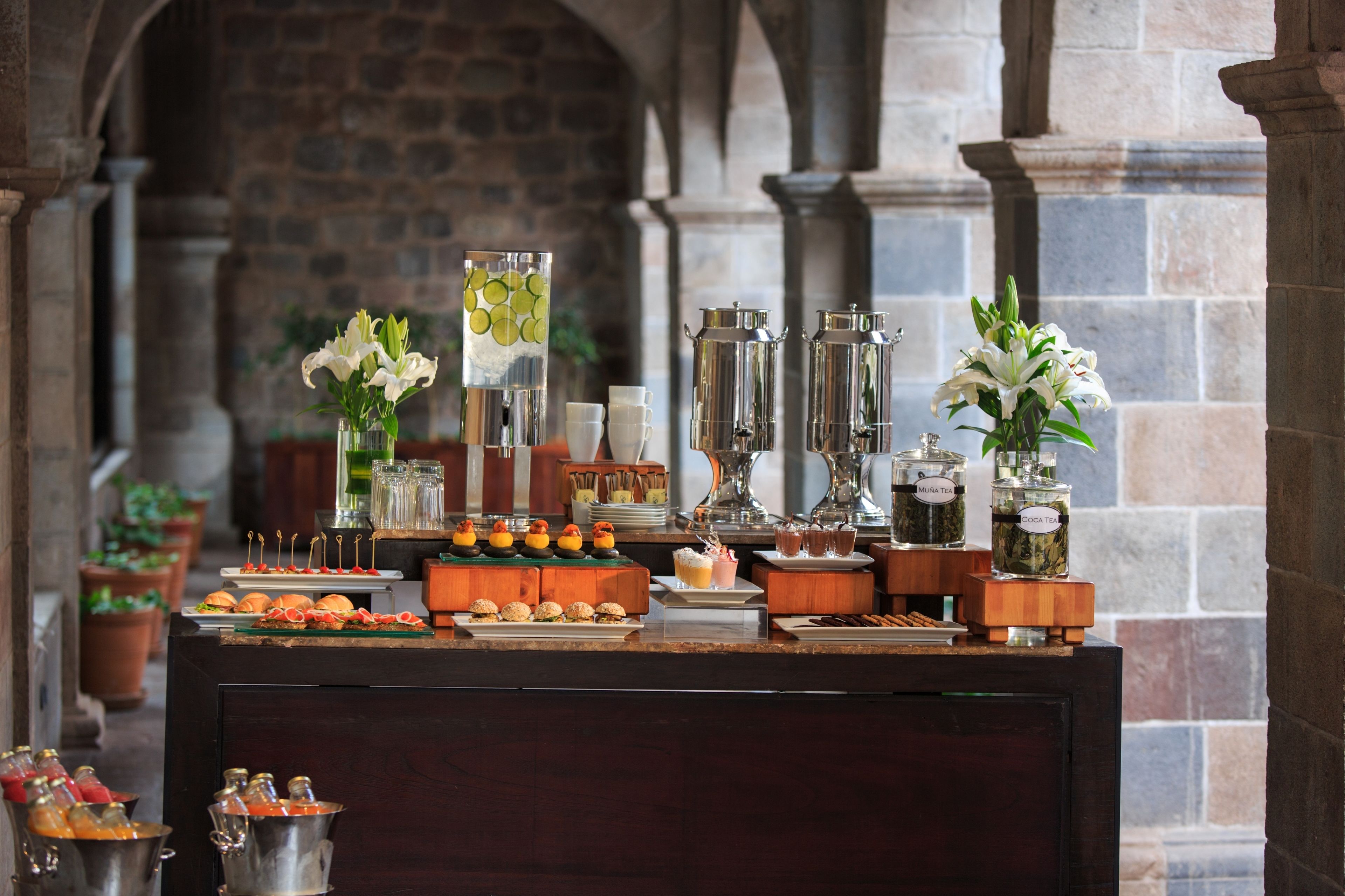 A buffet setup with various food items, drinks, and decorative flowers.