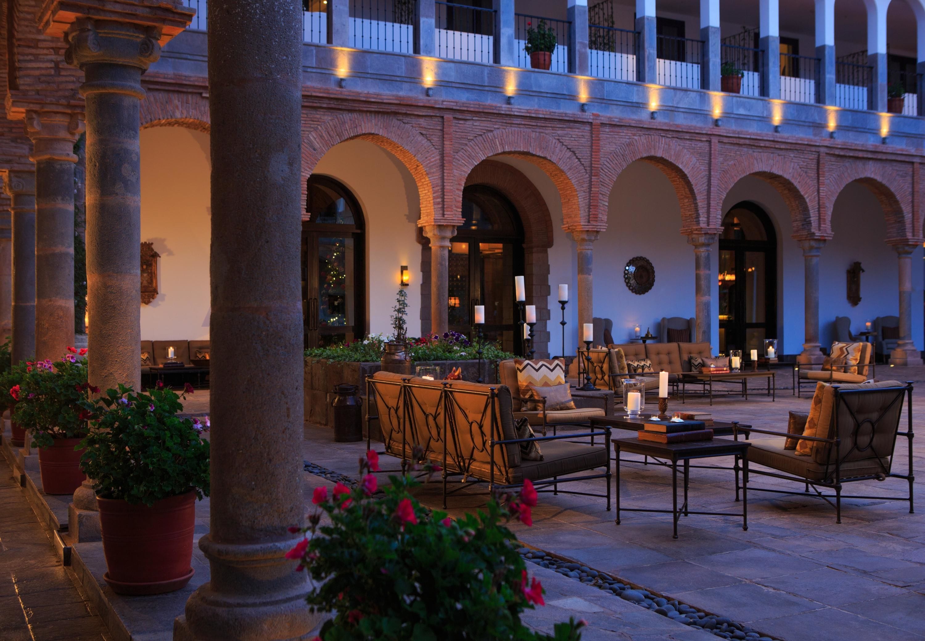 Un patio con mesas al aire libre, columnas y plantas en macetas.