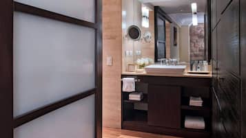 Un baño moderno con un espejo grande, tocador de madera y piso de baldosas.