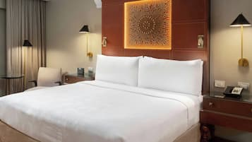 Una habitación de hotel con una cama grande, un escritorio con teléfono, una silla y una lámpara.
