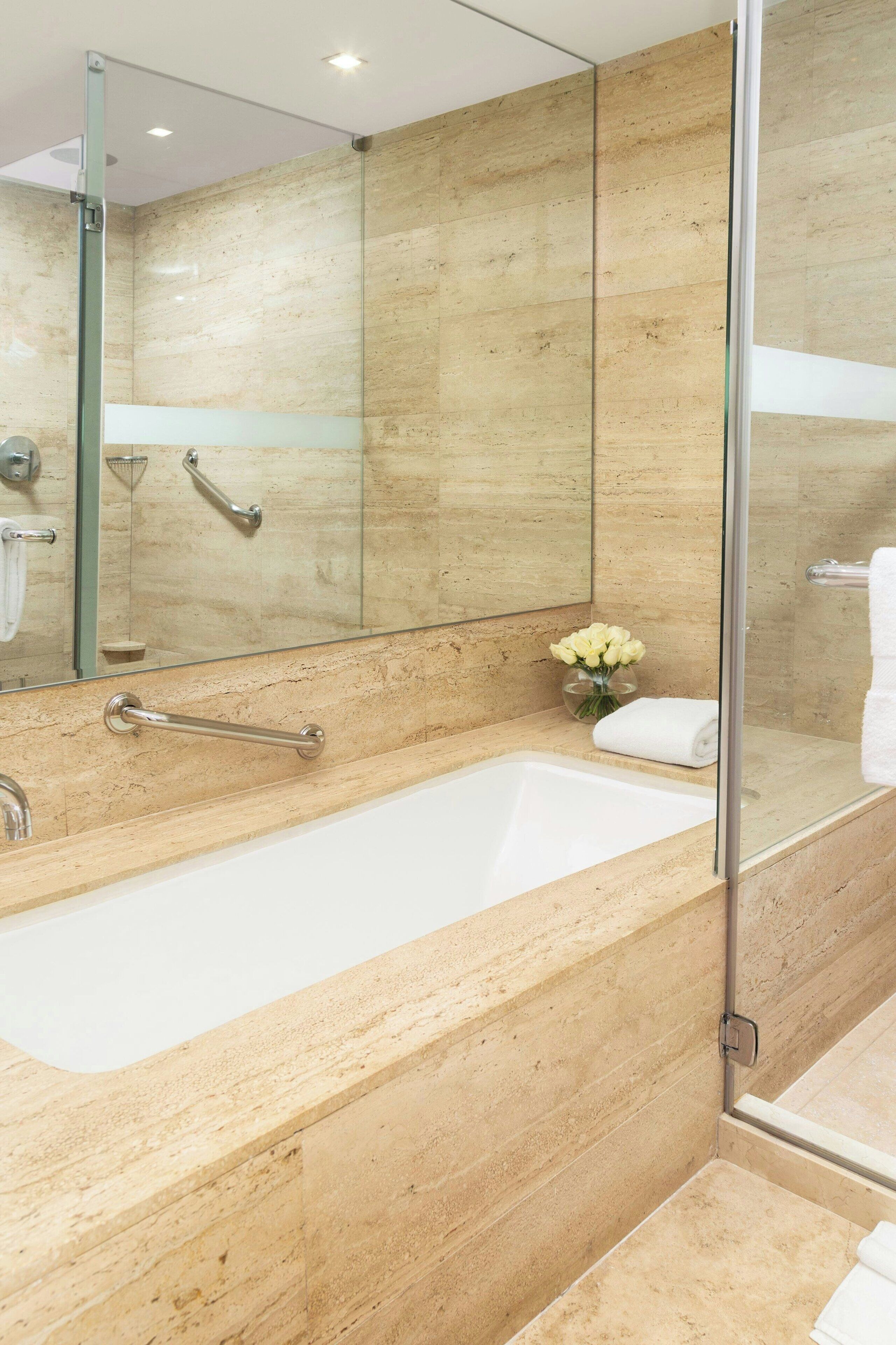 Un baño moderno con una bañera grande, una cabina de ducha de vidrio y una pared con azulejos de mármol.