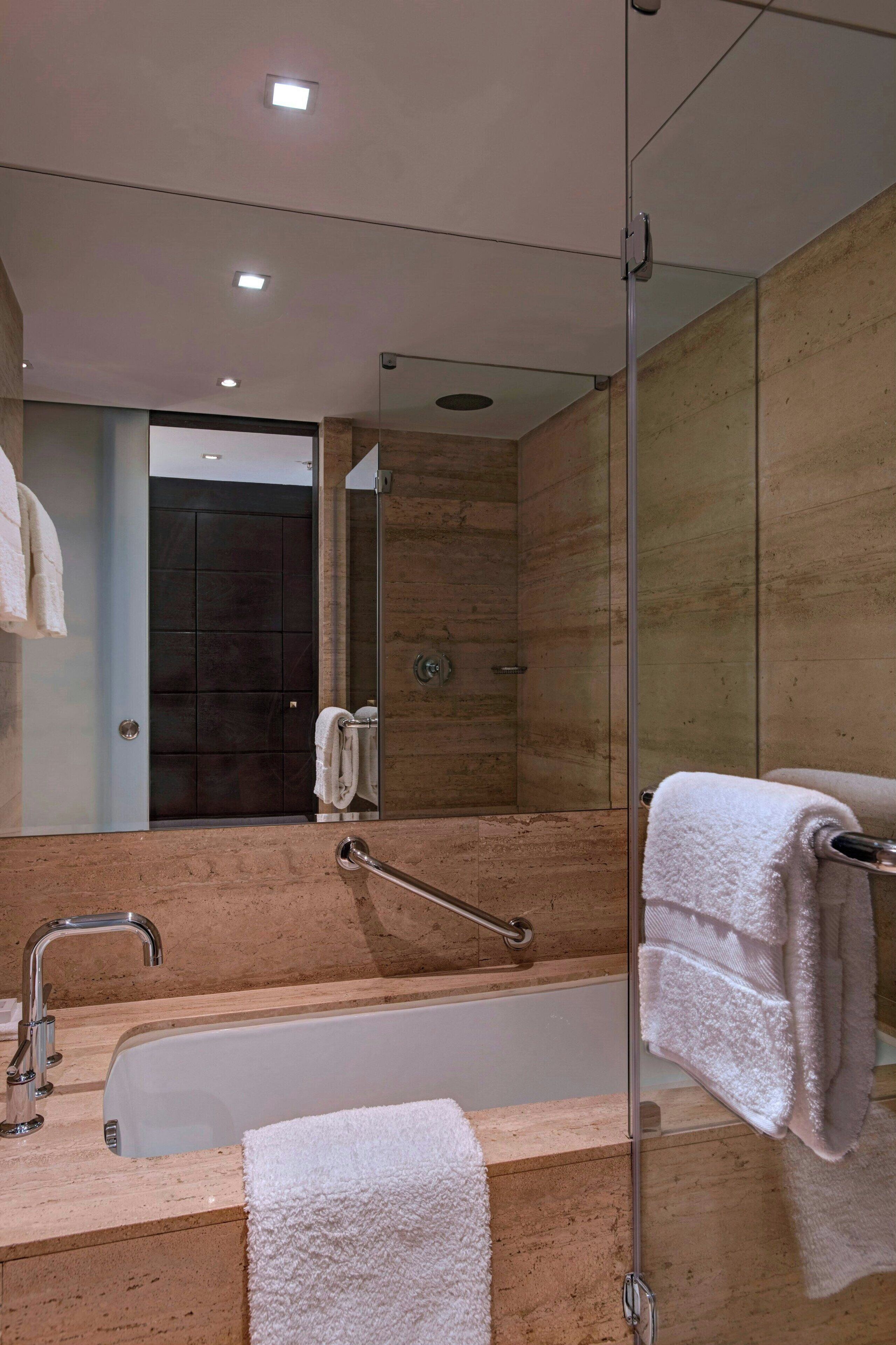 Une salle de bain moderne avec une douche à l’italienne, une baignoire et un grand miroir.