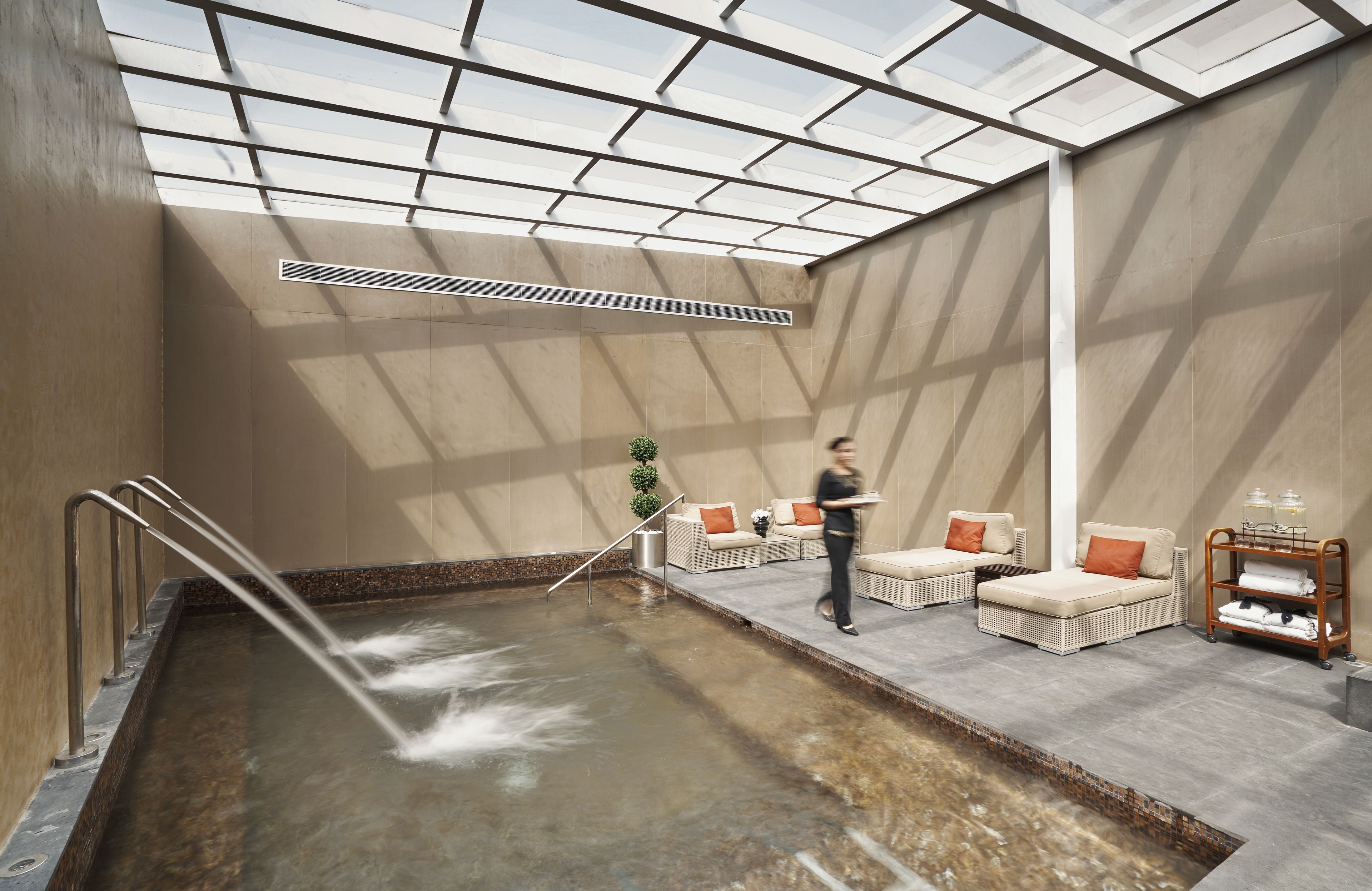 A spa area with a large indoor pool, seating, and a skylight.