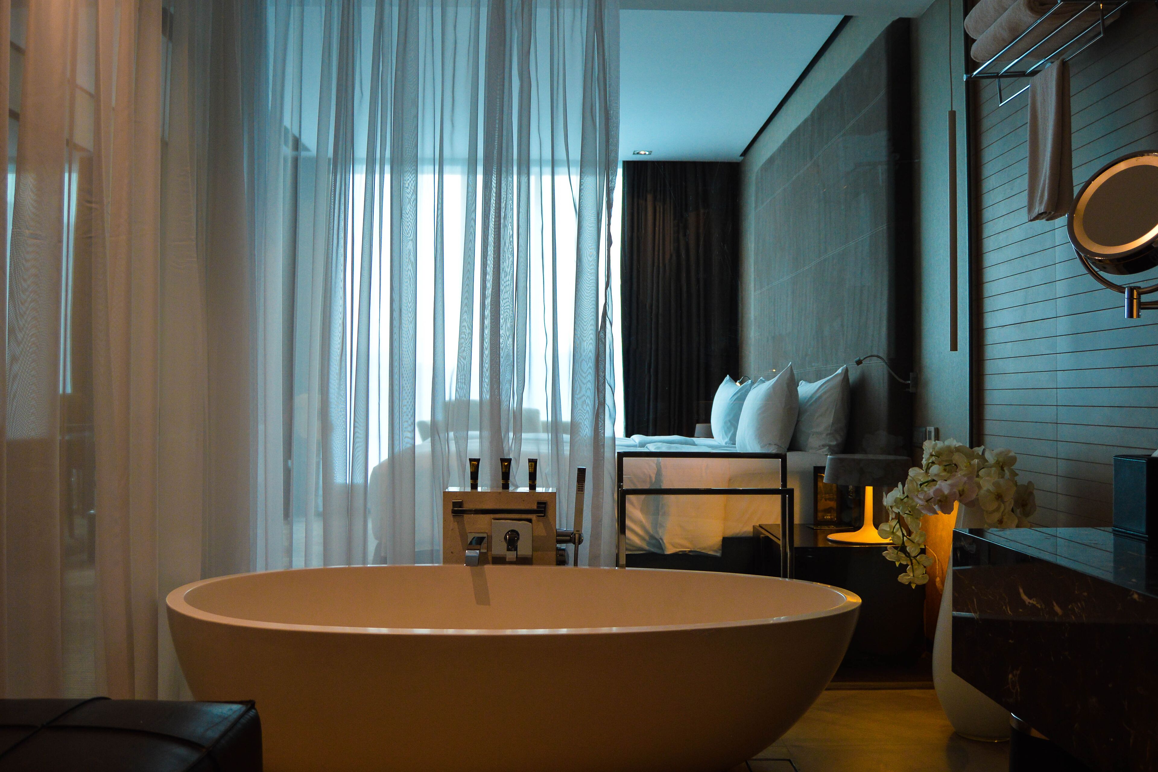 Un baño moderno con una bañera independiente, un tocador con espejo y una mesita de noche con lámpara.