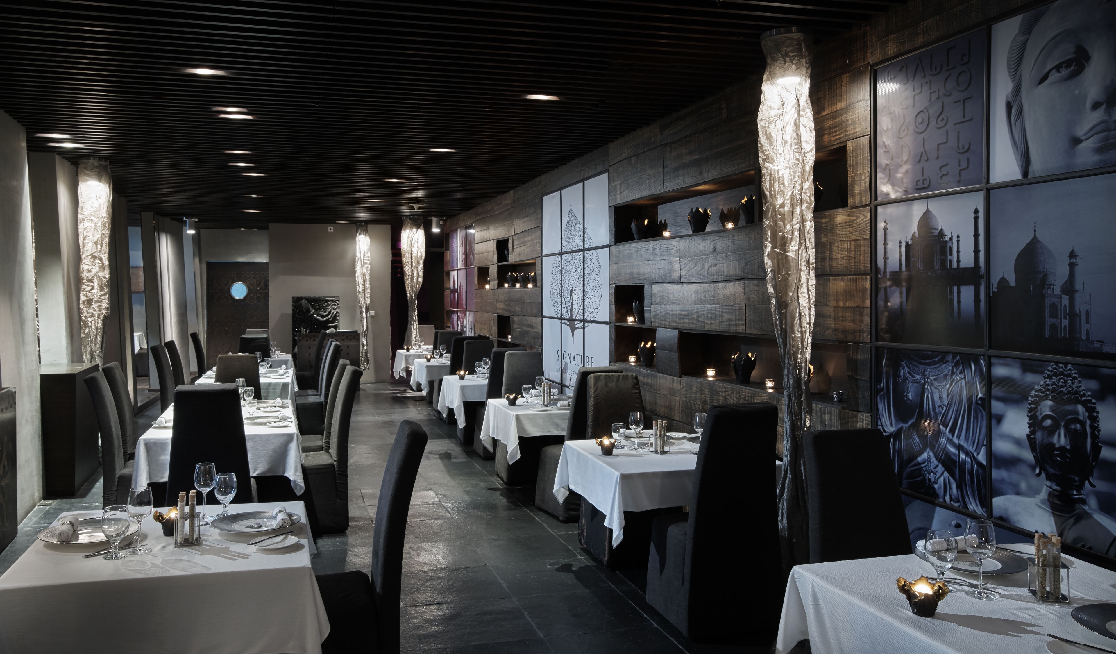 Un ristorante con lunghe tavolate, candele e quadri appesi alle pareti.