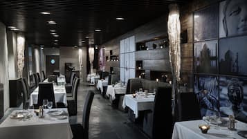A restaurant with long tables, candles, and framed artwork on the walls.