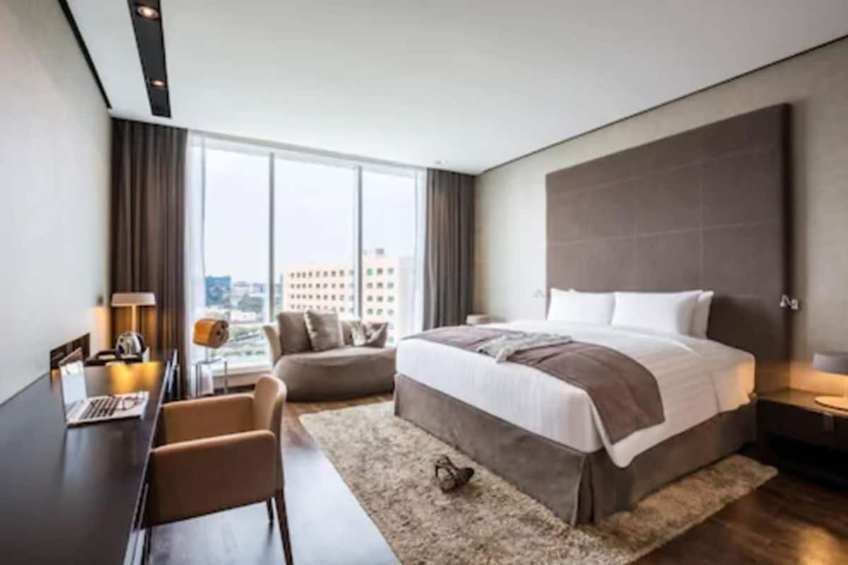 Ein modernes Hotelzimmer mit einem großen Bett, einem Schreibtisch und Blick auf die Stadt.
