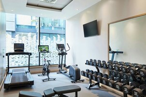 A gym with treadmills, stationary bikes, and a variety of dumbbells.