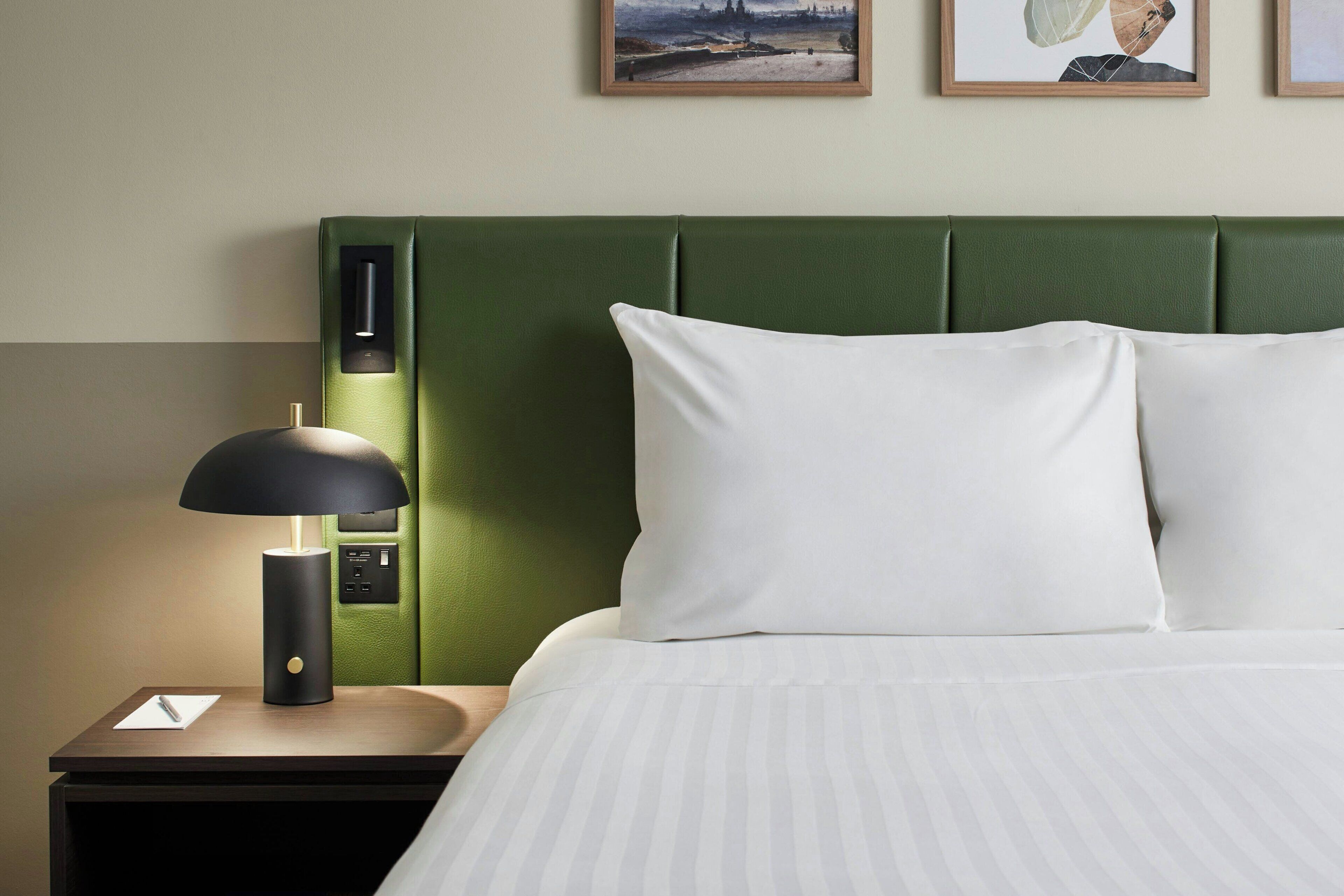 A neatly made bed with white pillows and a green headboard.