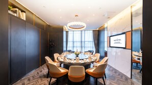 A conference room with a round table, chairs, and a chandelier. - Novotel Zhengzhou Convention Centre (Zhengzhou)