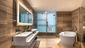 Une salle de bain moderne avec un grand miroir, deux lavabos, une baignoire et une douche à l’italienne.