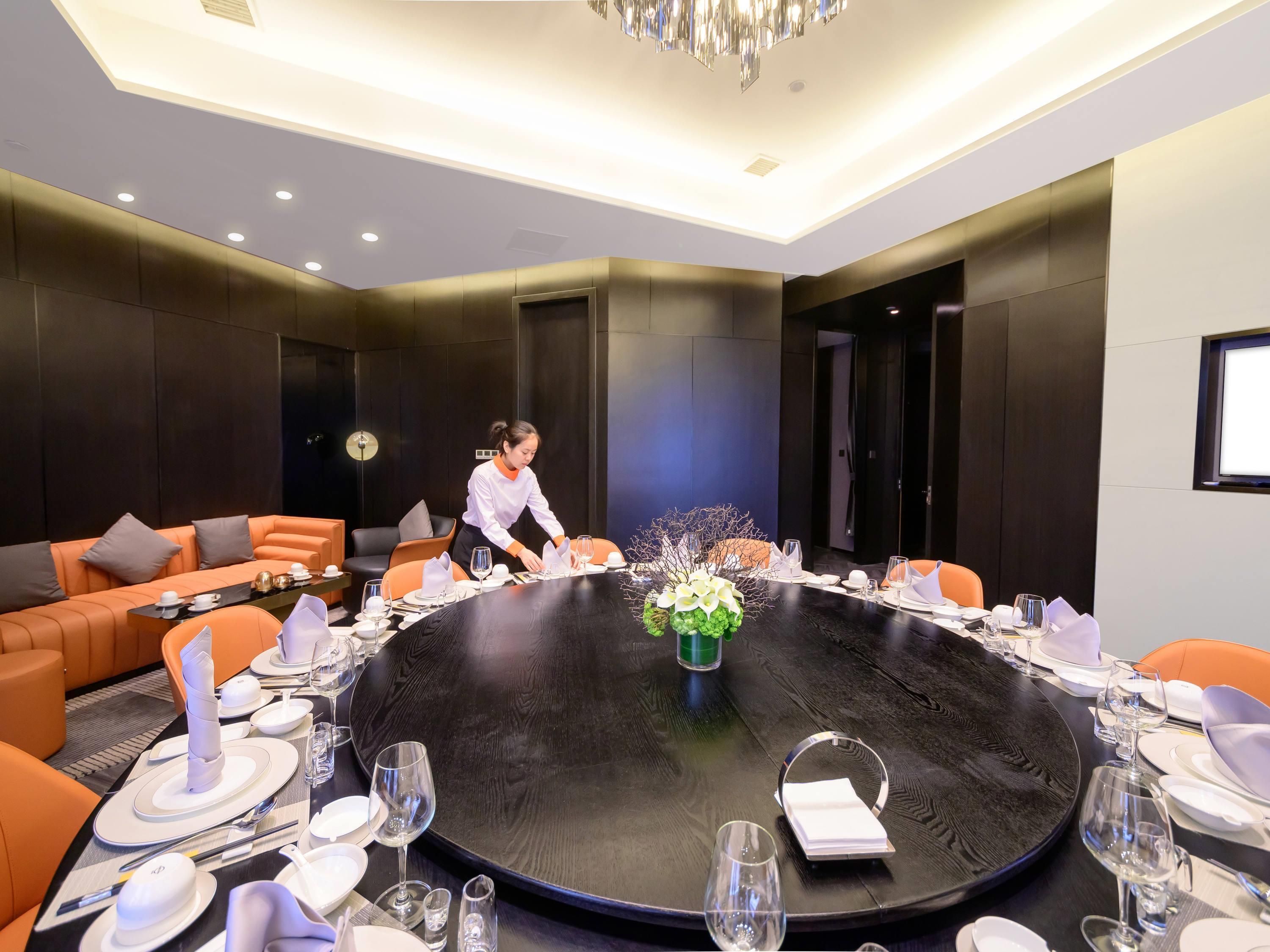 A conference room with a round table, orange seating, and a chandelier.