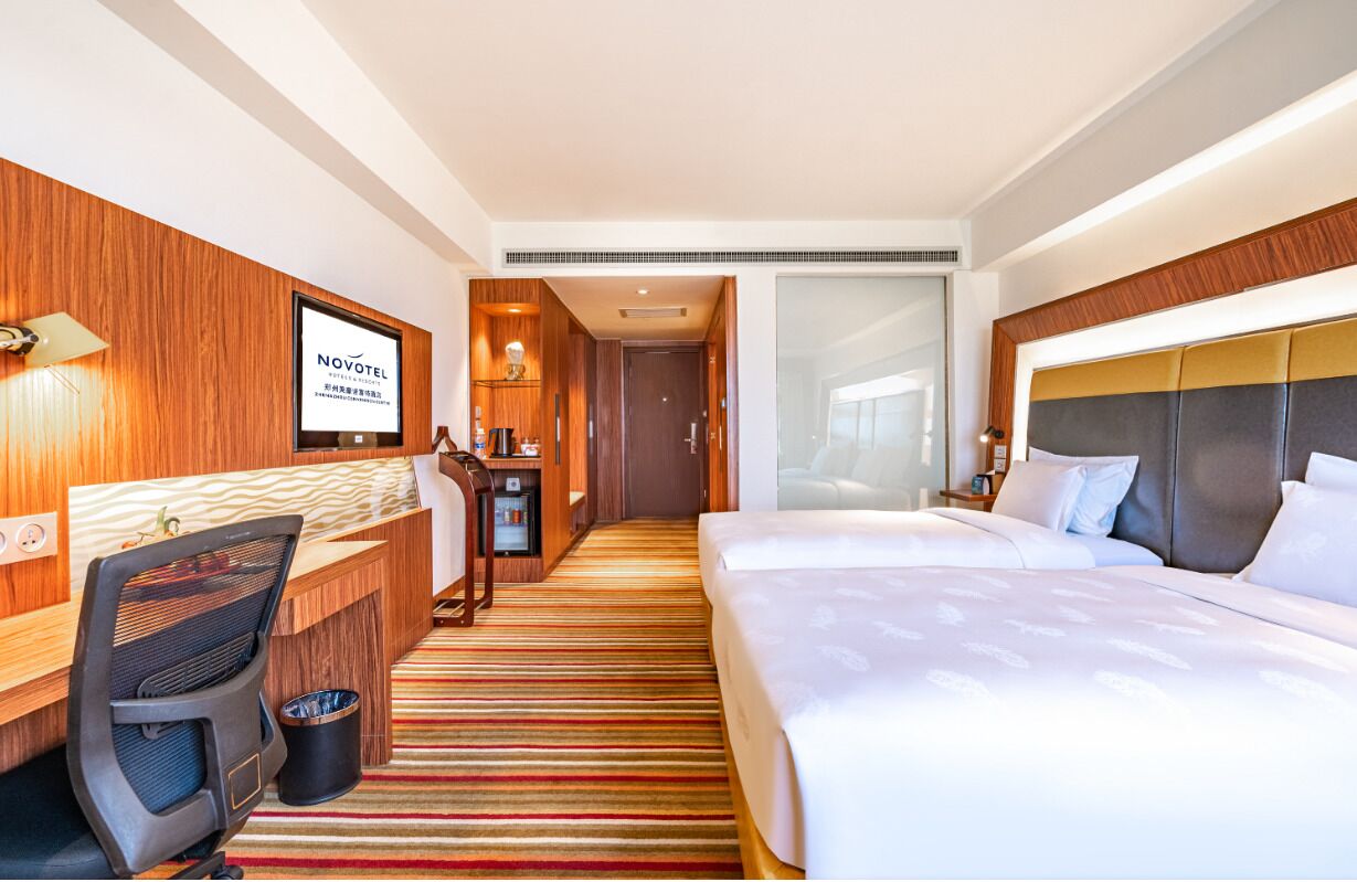 A hotel room with a bed, desk, chair, and a minibar.