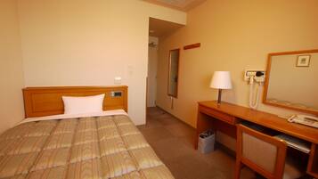 A hotel room with a bed, a desk, a chair, a telephone, and a mirror.