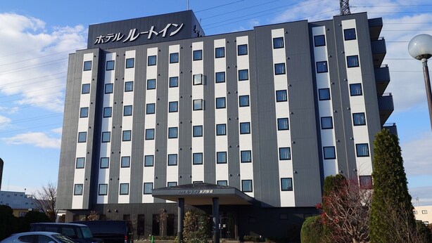 A modern hotel building with a prominent sign, multiple windows, and a parking area with cars. - Hotel Route-Inn Yonezawa Ekihigashi (Yonezawa)