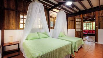 Una habitación con dos camas, paredes de madera, una mesita y un sofá rojo.