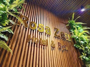 A wooden wall with the text 'Rosa Zee Hotel & Spa' and vertical wooden slats.
