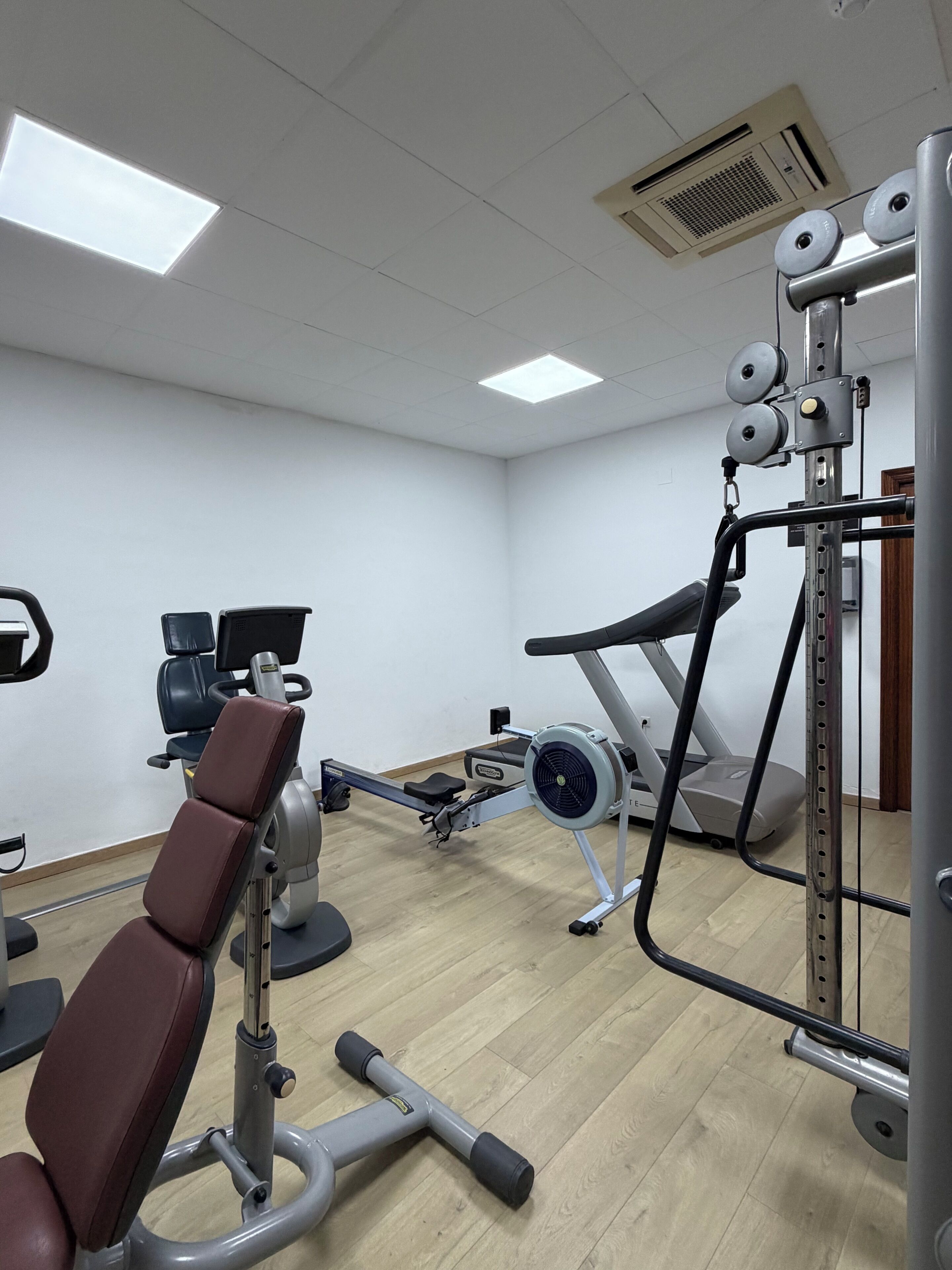 A gym with exercise equipment, a treadmill, and a rowing machine.
