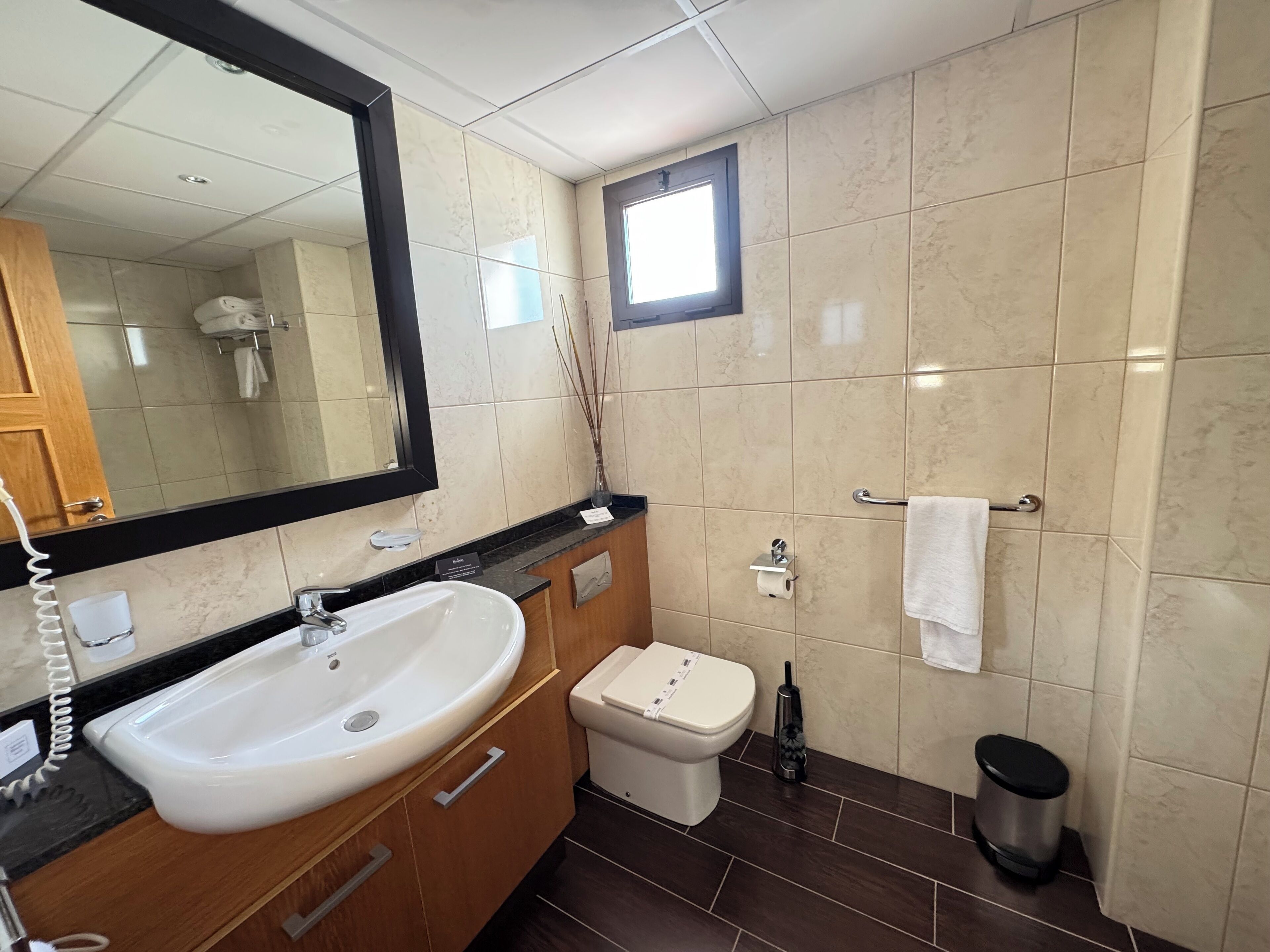Une salle de bain moderne avec un grand miroir, un lavabo blanc et des toilettes.
