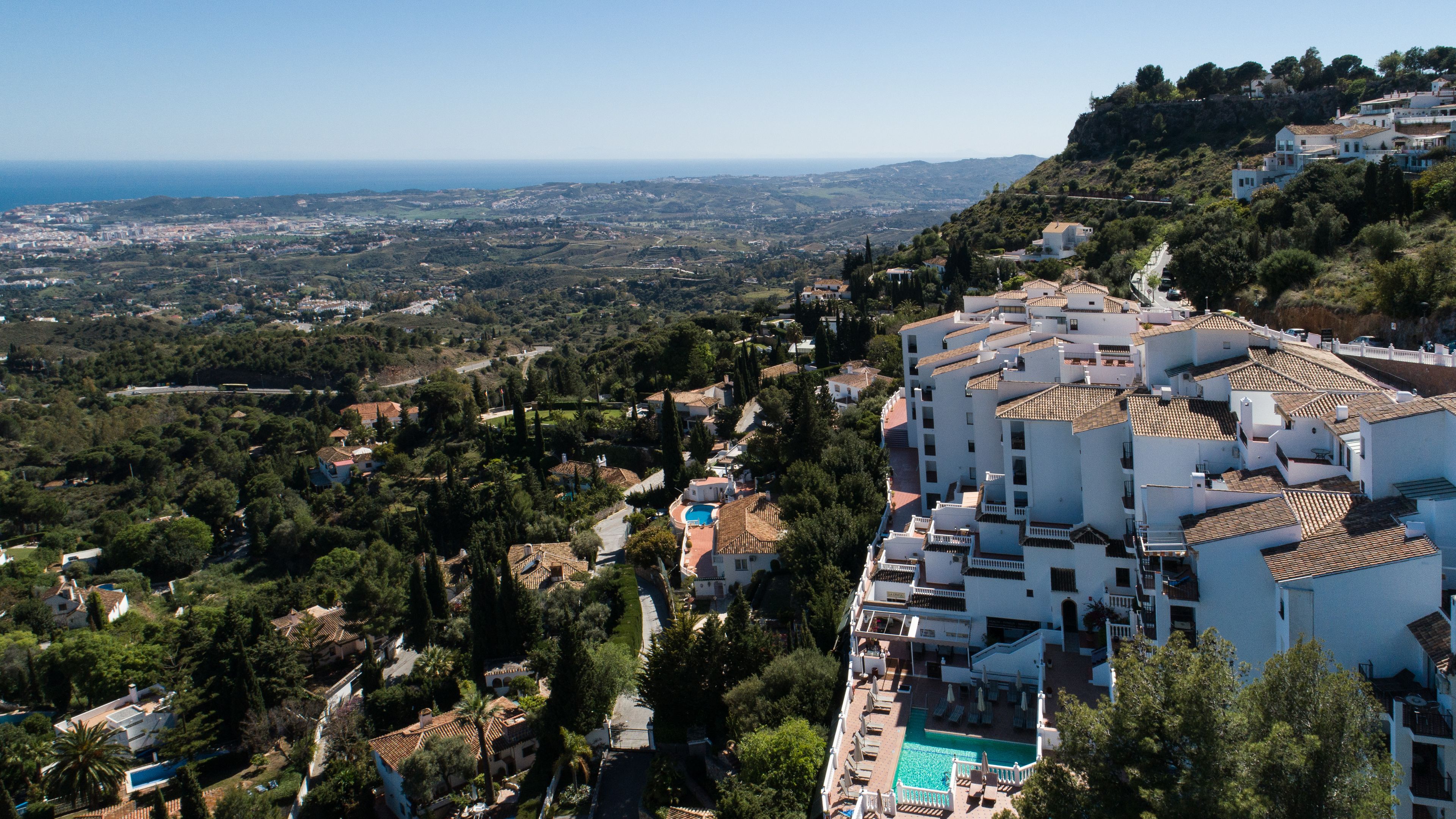 A coastal residential area with a view of the sea, a swimming pool, and terraced houses.