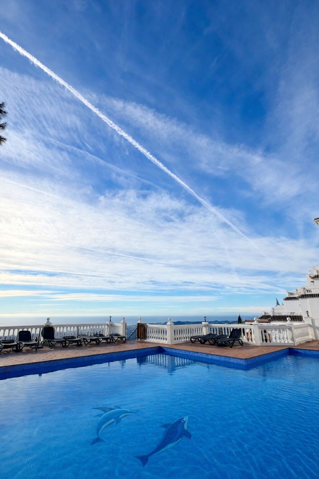 A swimming pool with a clear sky and a distant view of the ocean.