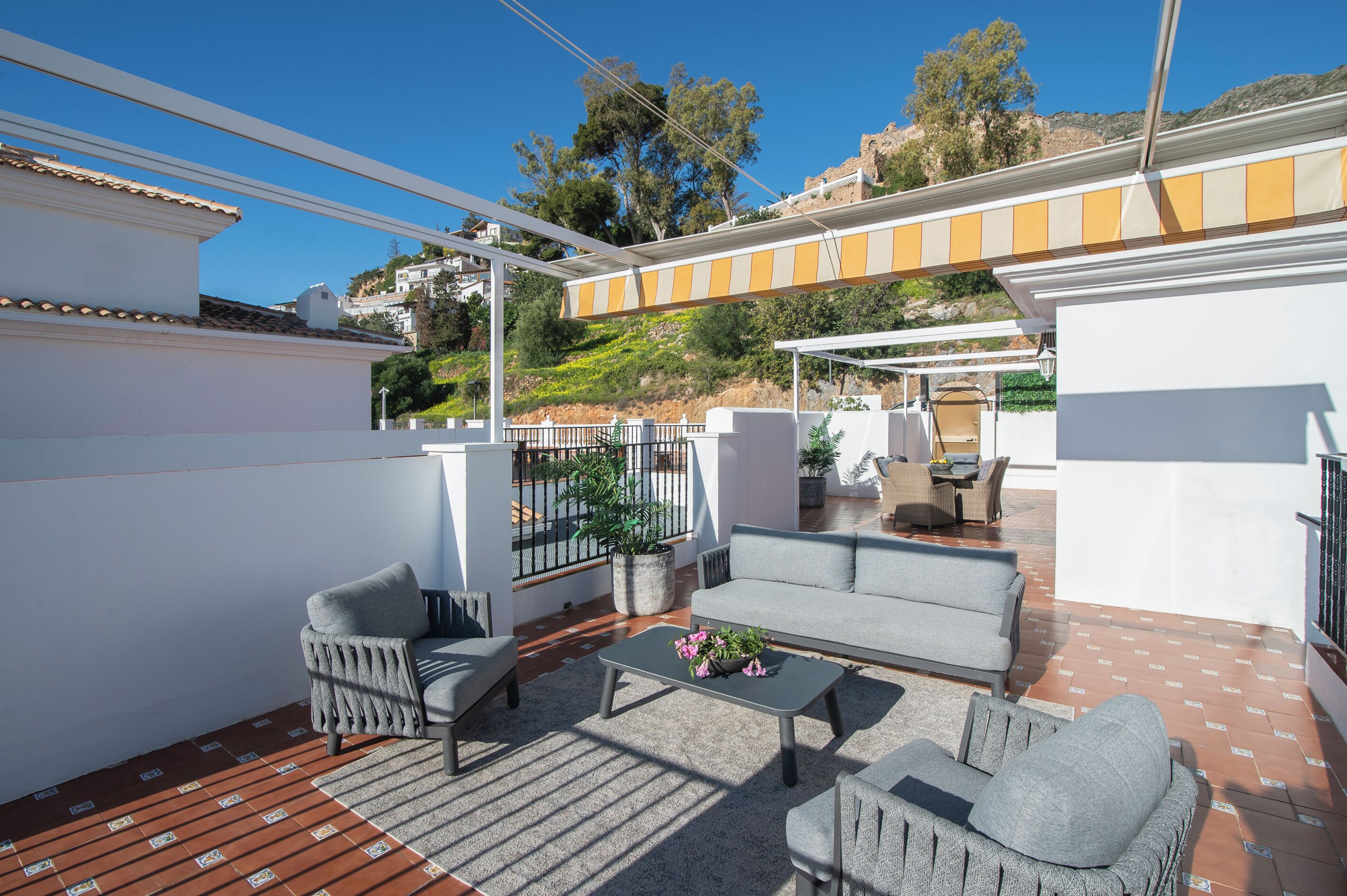 A covered outdoor seating area with a sofa, chairs, and a coffee table.