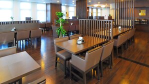 A modern restaurant with wooden tables and booths, large windows, and a central plant. - Hotel Route Inn Sagamihara -Kokudo 129 Gou (Sagamihara)