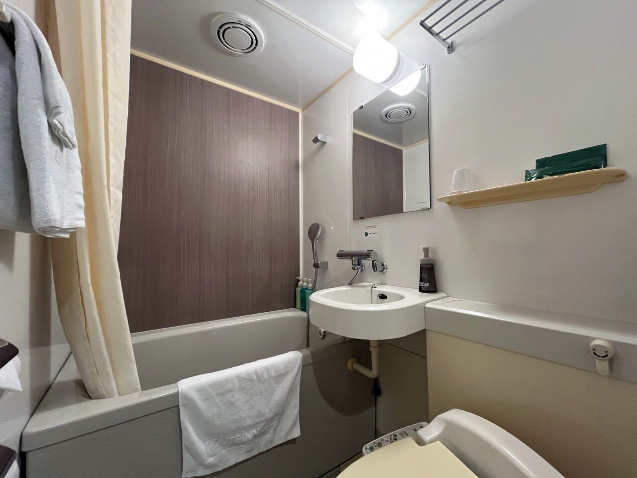 A bathroom with a bathtub, a sink, a mirror, and a towel rack.