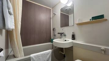 A bathroom with a bathtub, a sink, a mirror, and a towel rack.