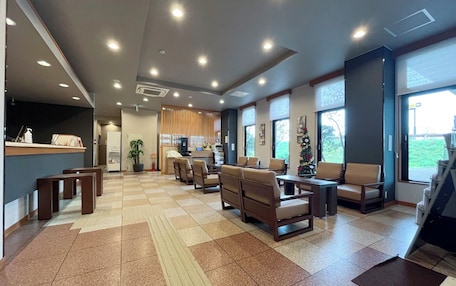A spacious lobby with a reception desk, seating area, and large windows offering a view of the outdoors.