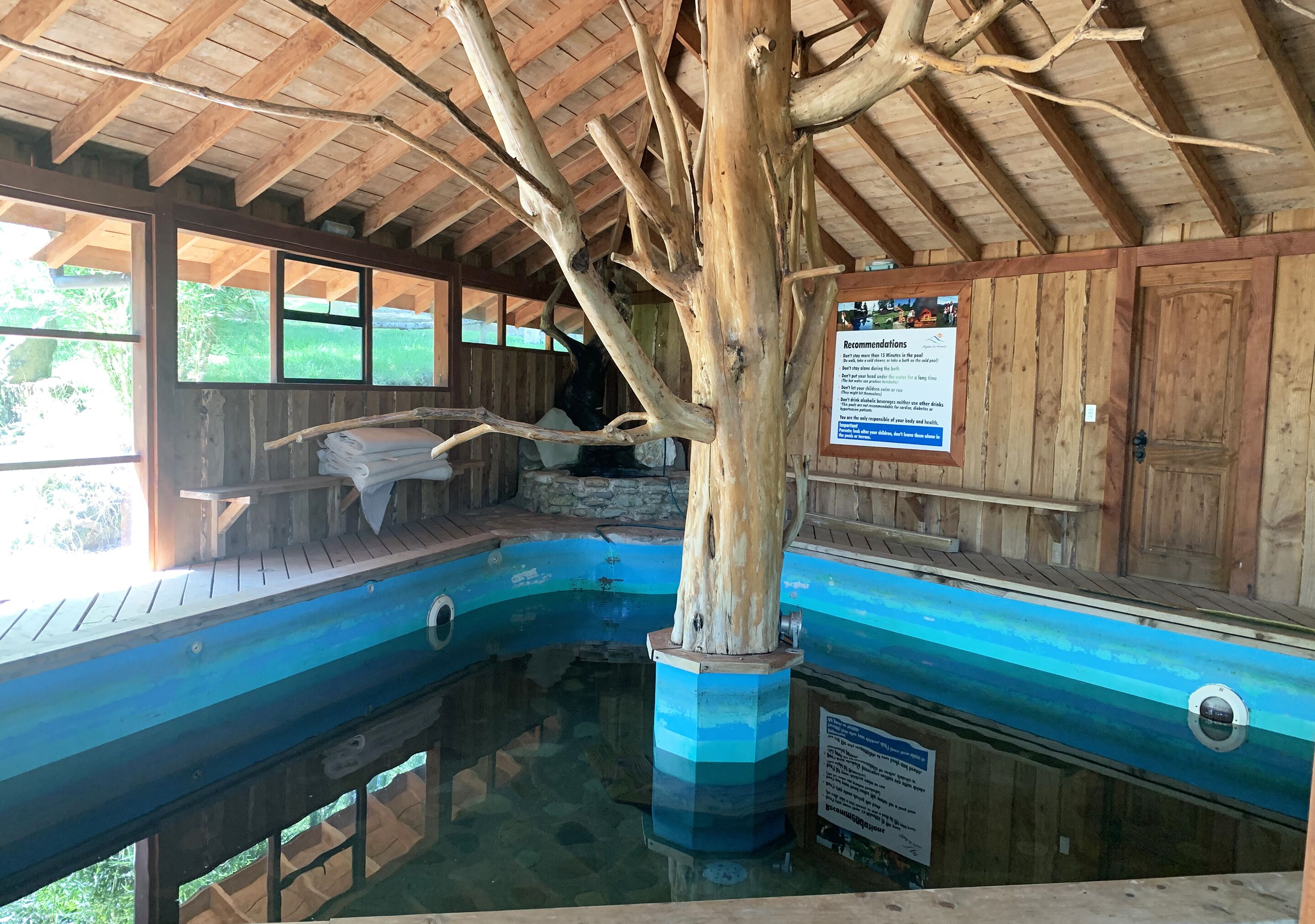 Una cabaña de madera con piscina, vigas de madera y un cartel con recomendaciones.