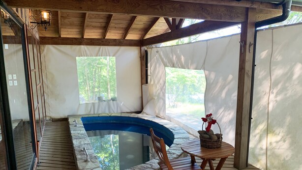A wooden deck with a hot tub, a table with a basket, and a chair. - Mirador Los Volcanes Lodge & Boutique (Pucón)