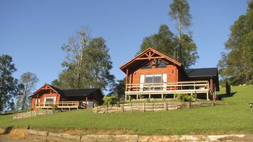 A rustic cabin with a wooden exterior, a balcony, and a stone retaining wall.