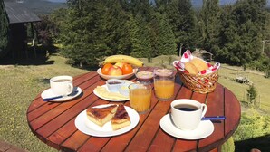 A wooden table with breakfast items and a mountain view. - Mirador Los Volcanes Lodge & Boutique (Pucón)