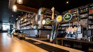 Eine Bar mit mehreren Zapfhähnen, einer Theke und Regalen voller Flaschen.