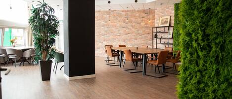 A modern indoor space with a brick wall, wooden flooring, and a large potted plant.