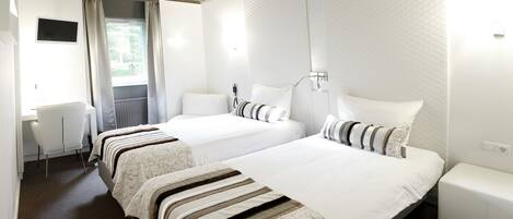 Habitación de hotel con dos camas, un escritorio y una silla.