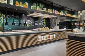 Una cocina moderna con salpicadero negro, listones de madera y diversos alimentos exhibidos en estantes.