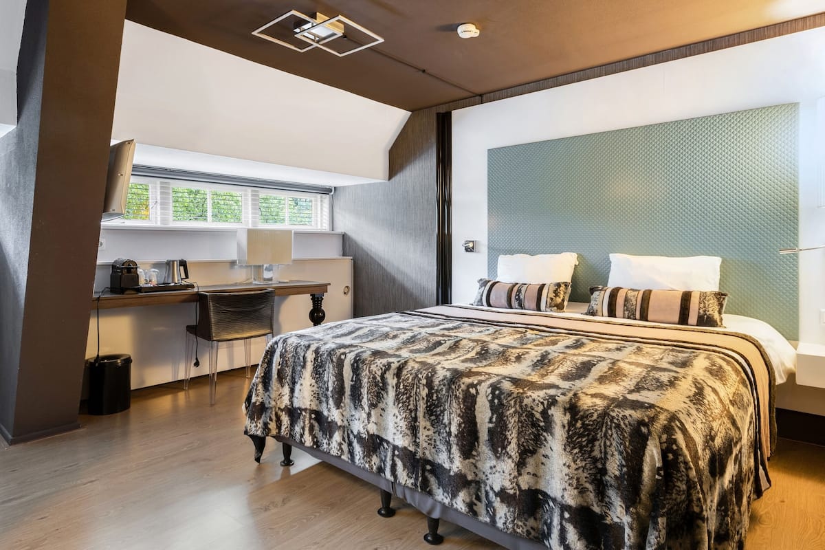 Un dormitorio con una cama grande, un escritorio y una ventana.